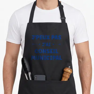 Tablier de cuisine noir avec l'inscription bleue J'peux pas j'ai conseil municipal encadrée par des flèches directionnelles.