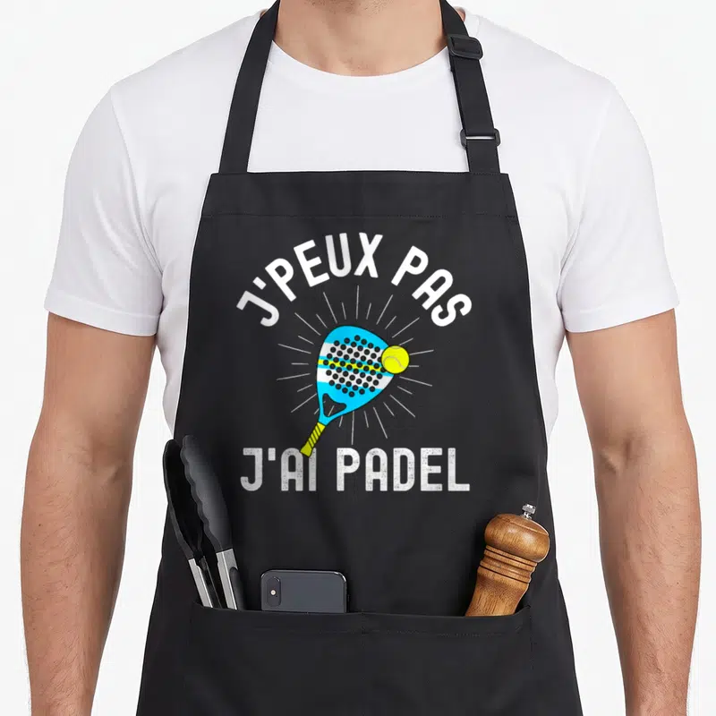 Tablier de cuisine noir avec une raquette de padel bleue, une balle jaune et le texte j'peux pas j'ai padel en blanc.