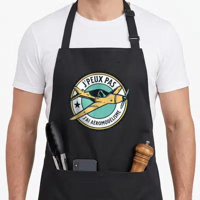 Tablier de cuisine noir avec logo circulaire affichant un avion jaune et l'inscription j'peux pas j'ai aéromodélisme.