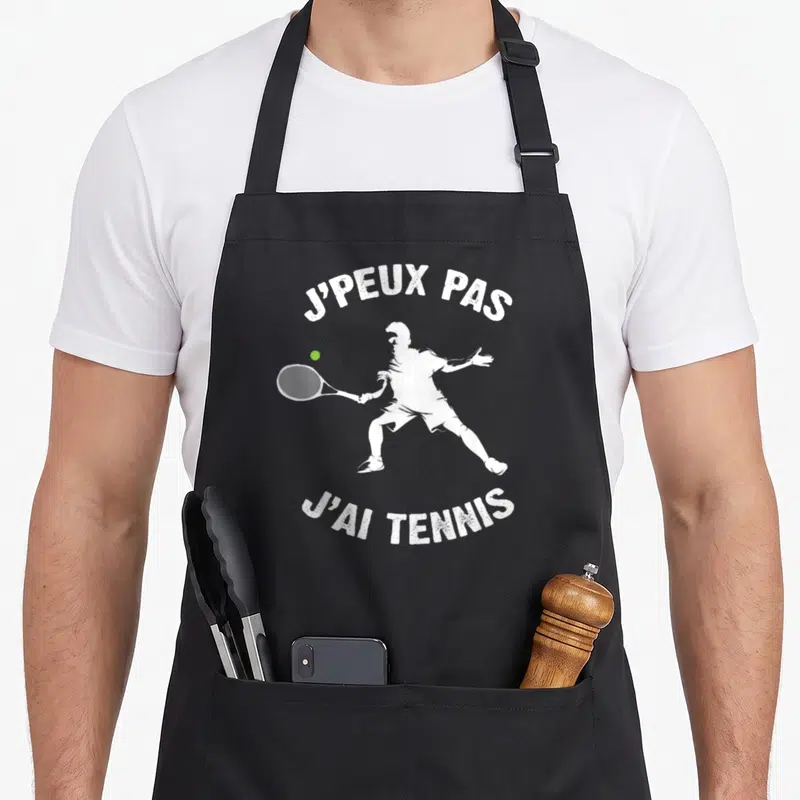 Tablier de cuisine noir avec silhouette blanche de joueur de tennis et texte j'peux pas j'ai tennis