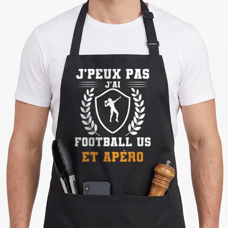 Tablier de cuisine noir avec inscription j'peux pas j'ai football US et apéro entouré d'une couronne de laurier blanche.