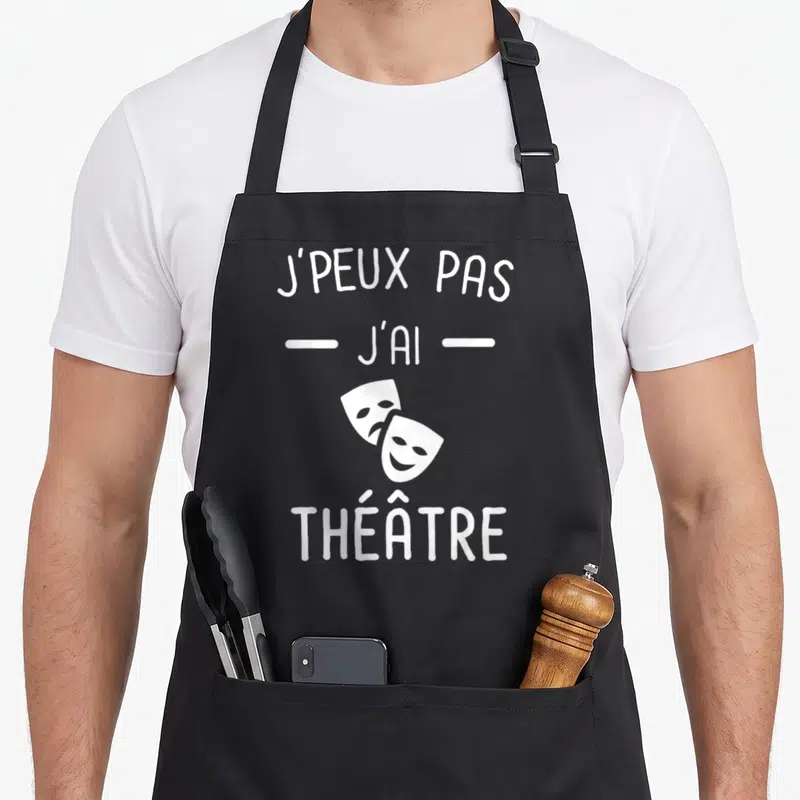 Tablier de cuisine noir avec inscription blanche J'peux pas j'ai théâtre et deux masques de théâtre superposés.
