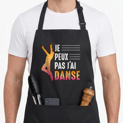 Tablier de cuisine noir avec silhouette dansante orange et texte blanc Je peux pas j'ai danse