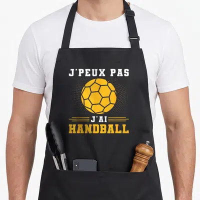 Tablier de cuisine noir avec une balle de handball orange et le texte j'peux pas j'ai handball maillot