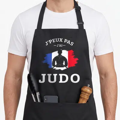 Tablier de cuisine noir avec silhouette judoka et drapeau français imprimés en blanc, bleu et rouge.