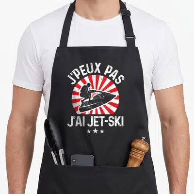 Tablier de cuisine noir avec motif j'peux pas j'ai jet-ski et silhouette de planche à moteur sur fond de rayons rouges.