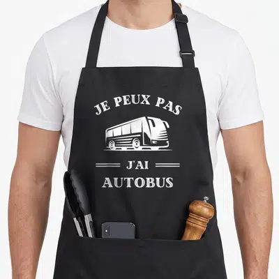 Tablier de cuisine noir avec inscription je peux pas j'ai autobus et dessin de bus blanc stylisé au centre.