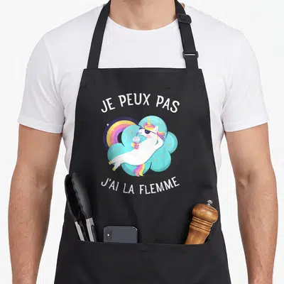 Tablier de cuisine noir avec une licorne relaxant sur un arc-en-ciel et le texte je peux pas j'ai la flemme.