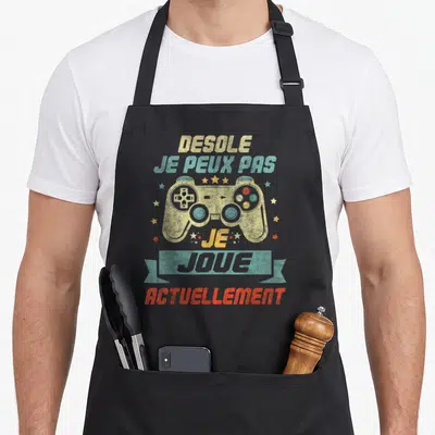 Tablier de cuisine noir avec manette de jeu vidéo vintage et texte désolé je peux pas je joue actuellement.