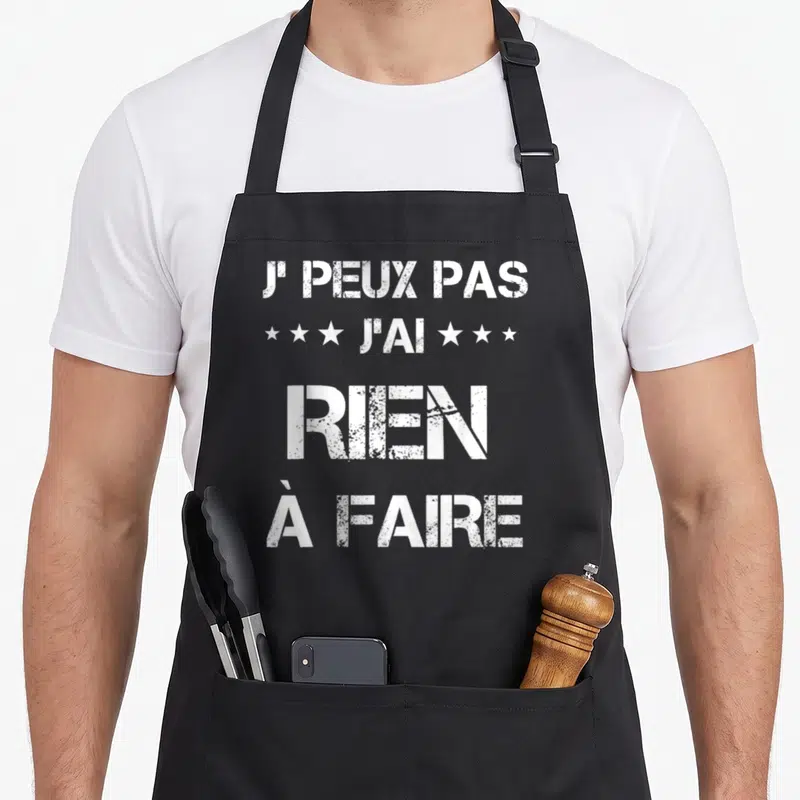 Tablier de cuisine noir avec inscription blanche J'PEUX PAS J'AI RIEN À FAIRE et trois étoiles de chaque côté du texte central.