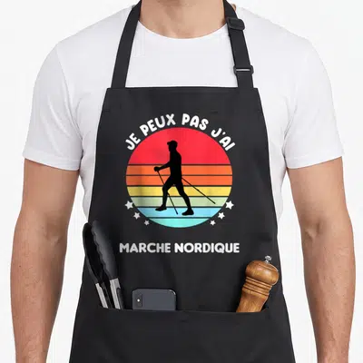 Tablier de cuisine noir avec silhouette de marcheur nordique sur fond circulaire coloré et texte blanc.