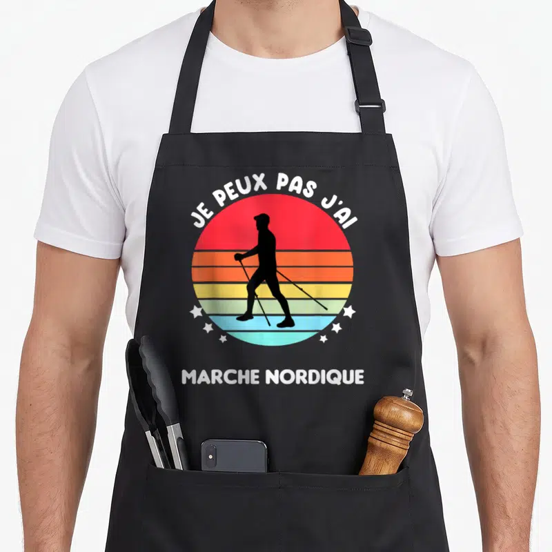 Tablier de cuisine noir avec silhouette de marcheur nordique sur fond circulaire coloré et texte blanc.