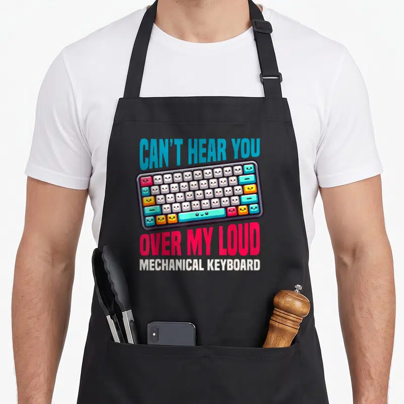 Tablier de cuisine noir avec illustration d'un clavier mécanique aux touches kawaii et texte Can't hear you over my loud mechanical keyboard.