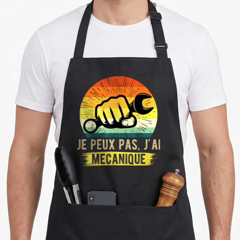 Tablier de cuisine noir avec illustration vintage d'un poing tenant une clé et le texte Je Peux Pas J'ai Mécanique.