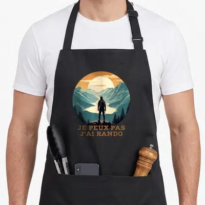 Tablier de cuisine noir avec silhouette randonneur et texte je peux pas j'ai rando sur fond de montagnes.