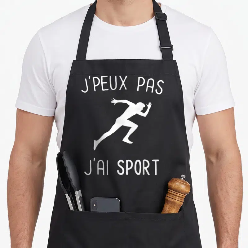 Tablier de cuisine noir avec une silhouette blanche de sprinter et le texte j'peux pas j'ai sport imprimé en haut et en bas.