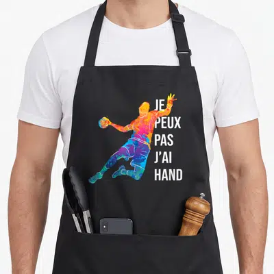 Tablier de cuisine noir avec silhouette multicolore d'un handballeur et le texte je peux pas j'ai hand imprimé en blanc.