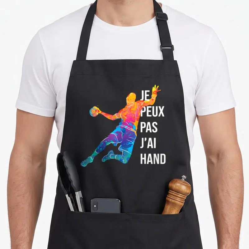 Tablier de cuisine noir avec silhouette multicolore d'un handballeur et le texte je peux pas j'ai hand imprimé en blanc.