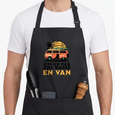 Tablier de cuisine noir avec illustration d'un van orange surmonté d'une planche de surf et d'un palmier au coucher du soleil.
