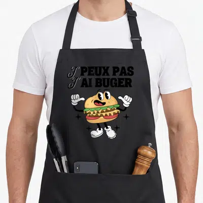 Tablier de cuisine noir avec un burger cartoon pointant vers lui-même et le texte J'PEUX PAS J'AI BUGER.