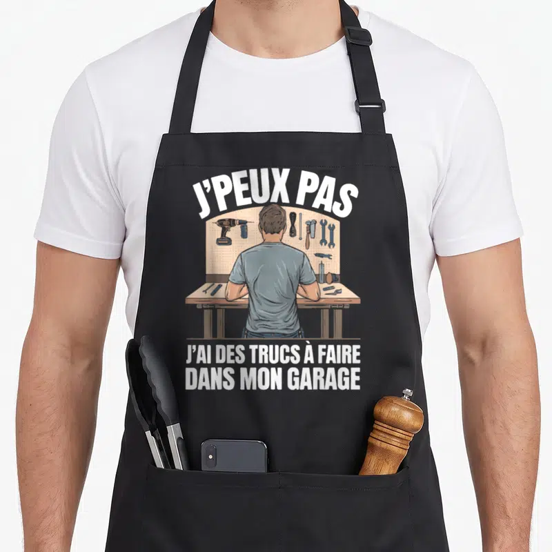 Tablier de cuisine noir avec illustration d'un homme face à un atelier et texte J'peux pas j'ai des trucs à faire dans mon garage