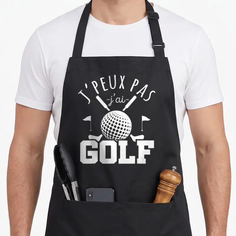 Tablier de cuisine noir avec une balle de golf, deux clubs croisés et le texte J'PEUX PAS J'AI GOLF en blanc.