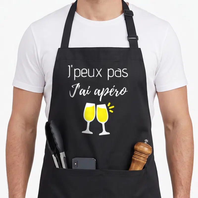 Tablier de cuisine noir avec l'inscription J'peux pas j'ai apéro et deux verres de champagne jaunes qui se touchent.