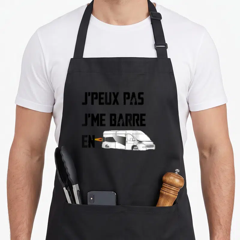 Tablier de cuisine noir avec l'inscription j'peux pas je me barre en van fourgon aménagé et une illustration de véhicule blanc.