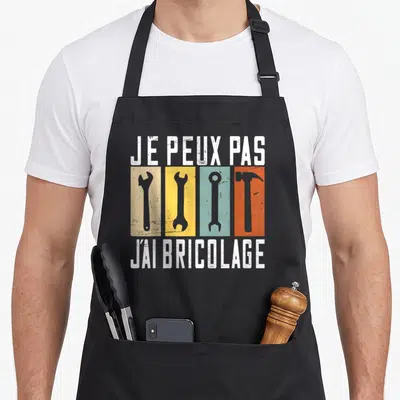 Tablier de cuisine noir avec texte blanc et icônes d'outils colorées sur fond rectangulaire vintage.