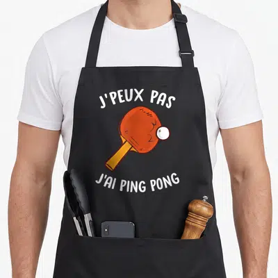 Tablier de cuisine noir avec une raquette de ping-pong orange et la mention j'ai ping pong en blanc.