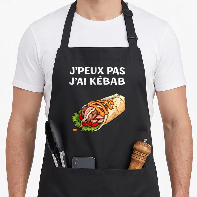 Tablier de cuisine noir avec illustration colorée d'un kebab garni et texte blanc humoristique.
