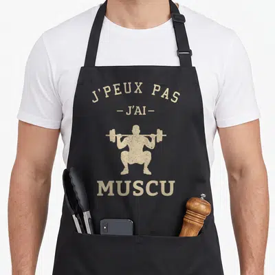 Tablier de cuisine noir avec silhouette beige d'un homme effectuant un squat sous une barre et le texte J'PEUX PAS J'AI MUSCU.
