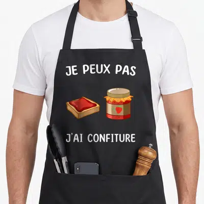 Tablier de cuisine noir avec illustration de pot de confiture et tartine, texte je peux pas j'ai confiture