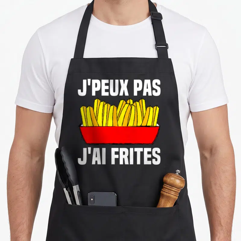 Tablier de cuisine noir avec un cornet de frites rouges et jaunes et le texte j'peux pas j'ai frites en blanc.