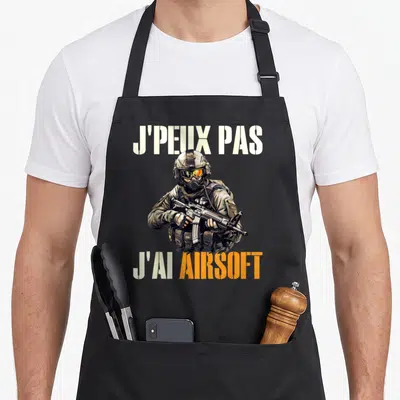 Tablier de cuisine noir avec illustration d'un soldat en tenue de camouflage tenant un airsofteur sous le texte J'peux pas j'ai Airsoft.