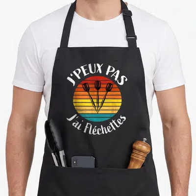 Tablier de cuisine noir avec illustration rétro de trois fléchettes et texte blanc J'peux pas j'ai fléchettes.