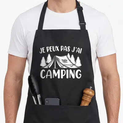 Tablier de cuisine noir avec une tente blanche entourée de pins et le texte je peux pas j'ai camping