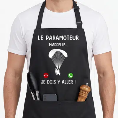 Tablier de cuisine noir avec illustration d'un paramoteur blanc et icônes de téléphone rouge et vert.