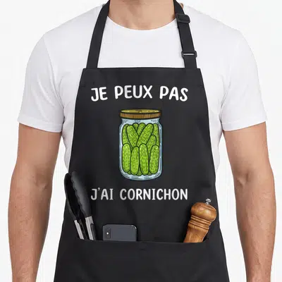 Tablier de cuisine noir avec illustration d'un bocal de cornichons verts et texte blanc.