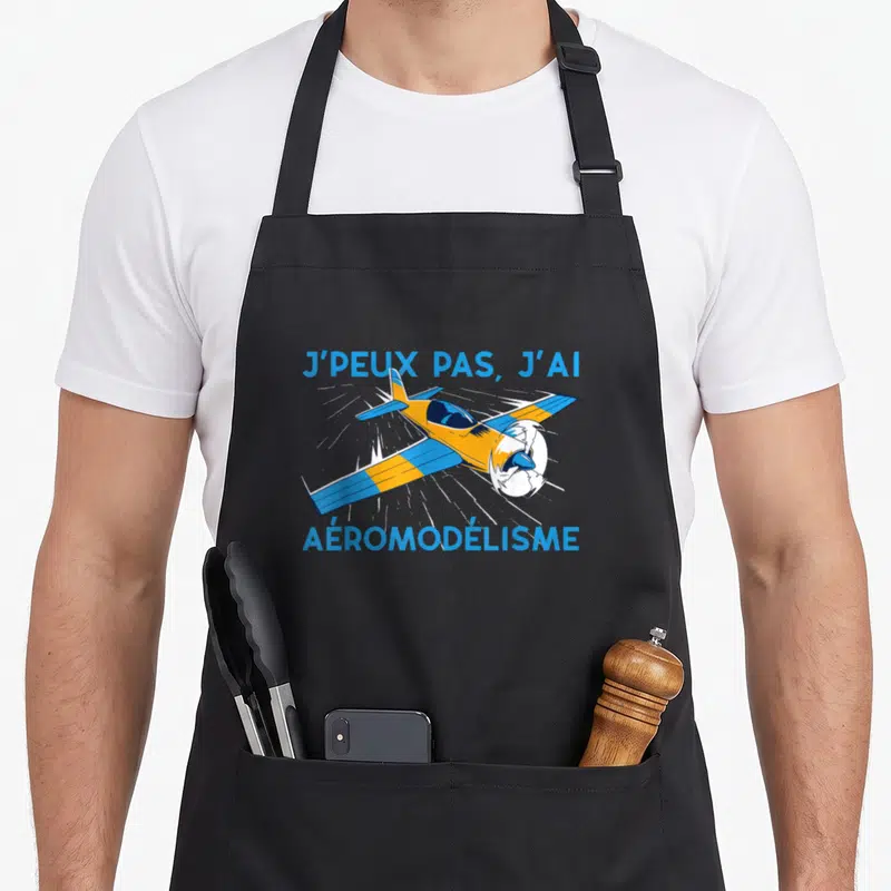 Tablier de cuisine noir avec avion orange et bleu et texte j'peux pas j'ai aéromodélisme imprimé en bleu.