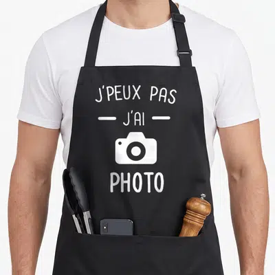 Tablier de cuisine noir avec inscription blanche J'peux pas j'ai photo et icône appareil photo stylisée au centre