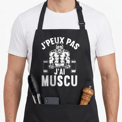 Tablier de cuisine noir avec illustration blanche d'un gorille musclé tenant une barre de poids et le texte J'PEUX PAS J'AI MUSCU.