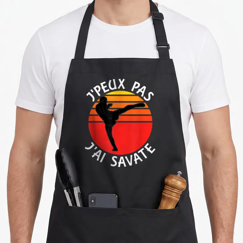 Tablier de cuisine noir avec silhouette de boxeur effectuant un coup de pied et le texte j'peux pas j'ai savate.