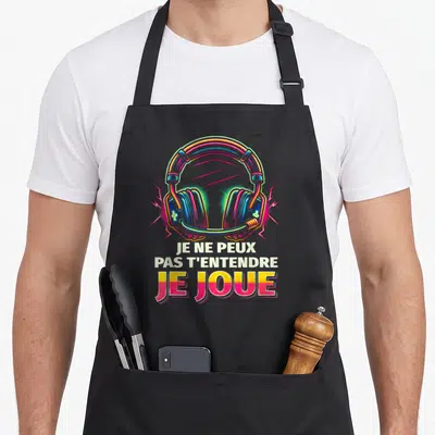 Tablier de cuisine noir avec illustration de casque de jeu vidéo multicolore et texte humoristique en lettres blanches et roses.