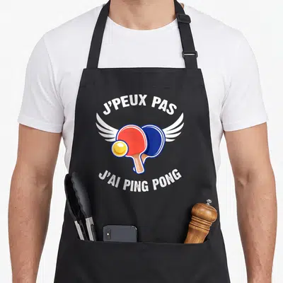 Tablier de cuisine noir avec deux raquettes de ping pong et le texte j'peux pas j'ai ping pong.