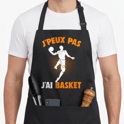 Tablier de cuisine noir avec illustration d'un basketteur et texte j'peux pas j'ai basket en orange et blanc.