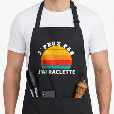 Tablier de cuisine noir avec motif soleil rétro et texte blanc J'peux pas j'ai raclette.