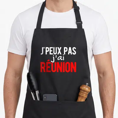 Tablier de cuisine noir avec l'inscription j'peux pas j'ai réunion en blanc et rouge.