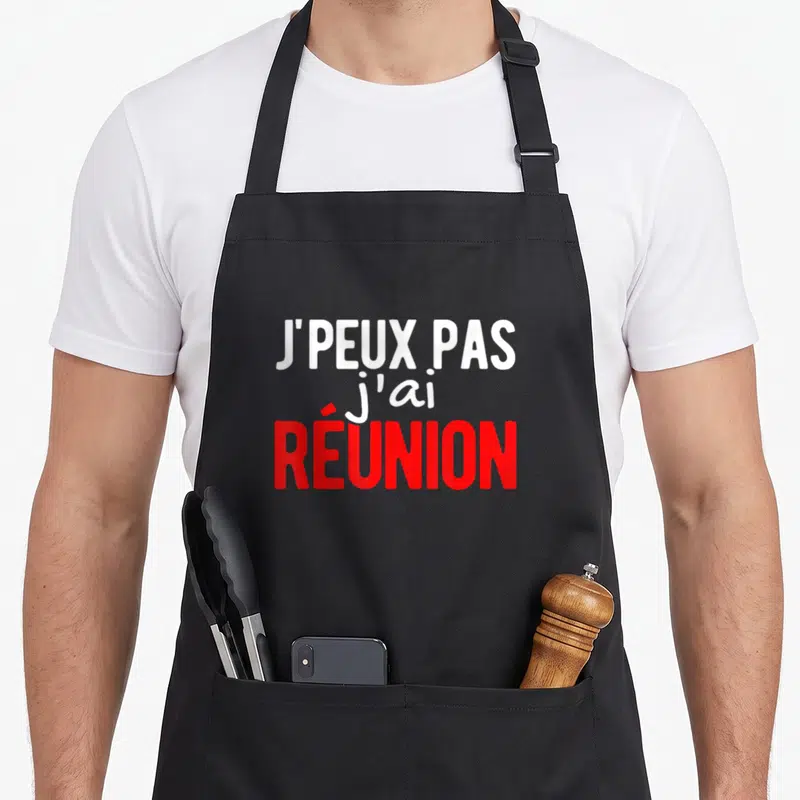 Tablier de cuisine noir avec l'inscription j'peux pas j'ai réunion en blanc et rouge.