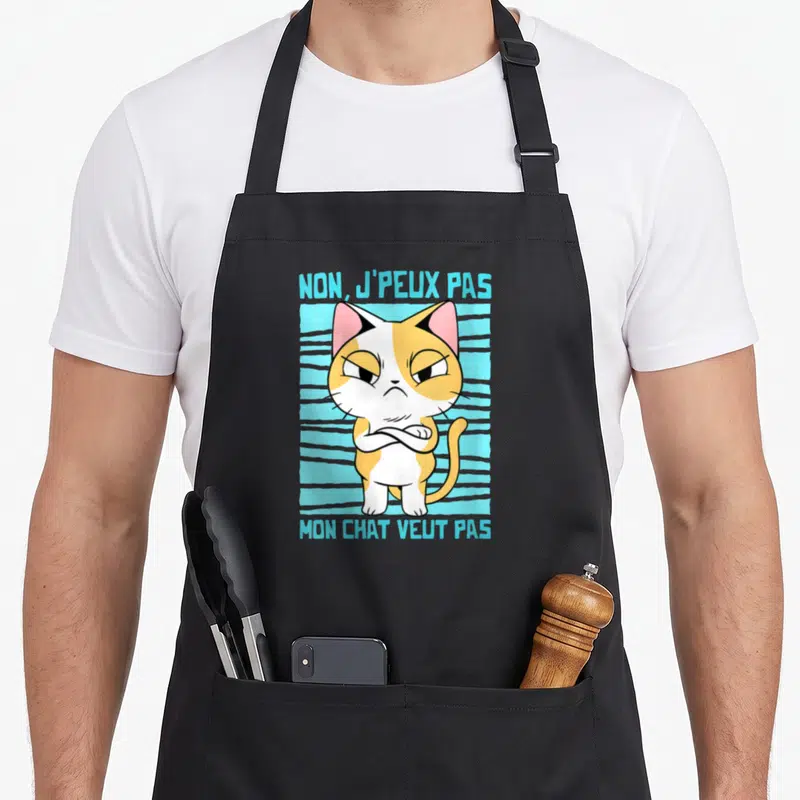 Tablier de cuisine noir avec illustration d'un chat tricolore aux bras croisés et texte bleu.